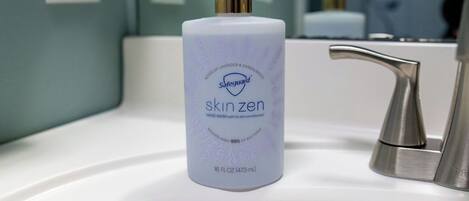 A bathroom sink with a bottle of Safeguard Skinzen hand wash.