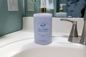 Un lavamanos de baño con una botella de jabón de manos Safeguard Skinzen.