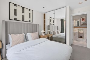 Ein modernes Hotelzimmer mit einem großen Bett, Nachttischen, einem Spiegel und einem Kleiderschrank.