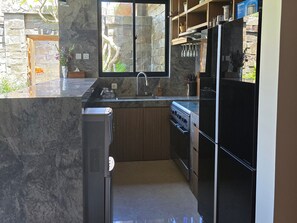 A kitchen with a stone backsplash, a built-in oven, and a refrigerator.