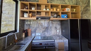 A kitchen with a stone backsplash, wooden shelves, a built-in oven, and a refrigerator. - Private Villa 4bedrooms with rooftop open pool (Gianyar)