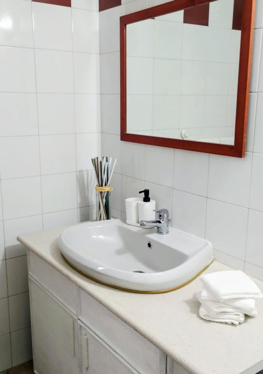 Ein Badezimmer mit einem weißen Waschbecken, einem Spiegel und einem Handtuch auf der Ablagefläche.