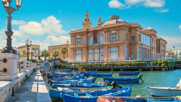 A waterfront with boats docked, a large building with domes, and a clear blue sky. - Just minutes from the city, perfect for everyone—including families with kids (play area) (Bari)