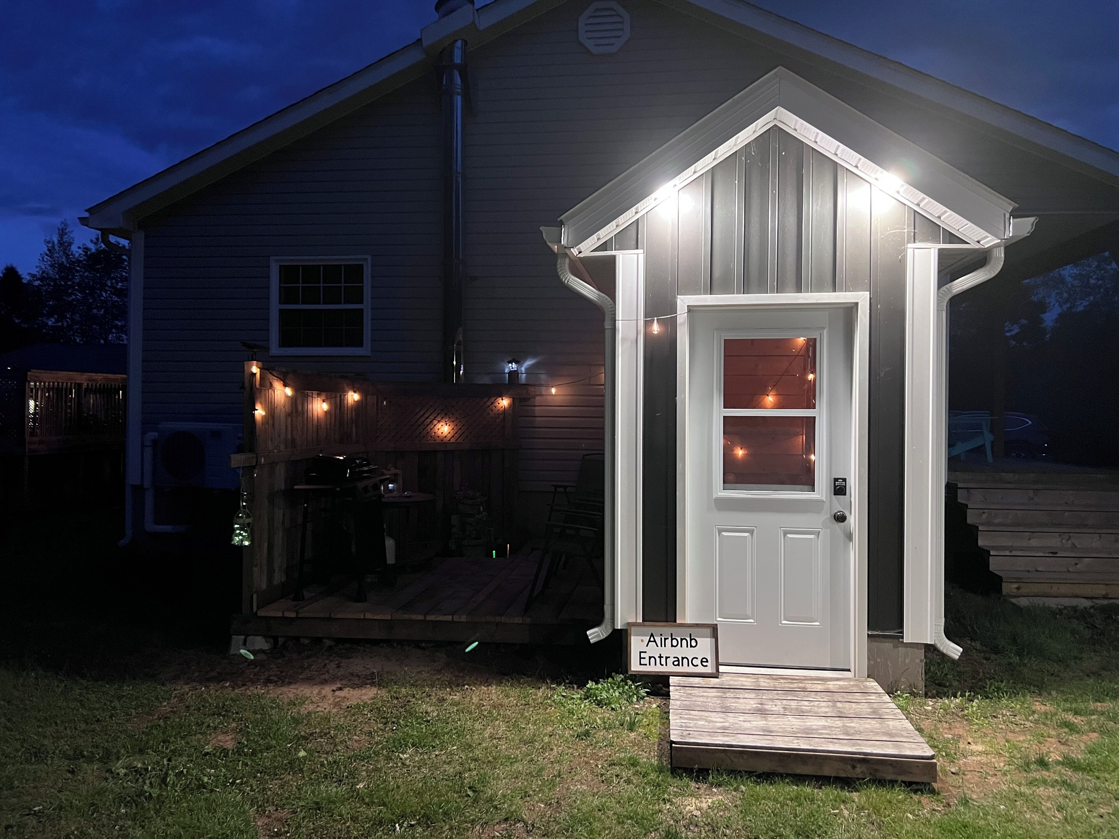 Une petite structure en bois portant l’inscription « Entrée Airbnb », avec une porte et une rampe menant à l’intérieur.
