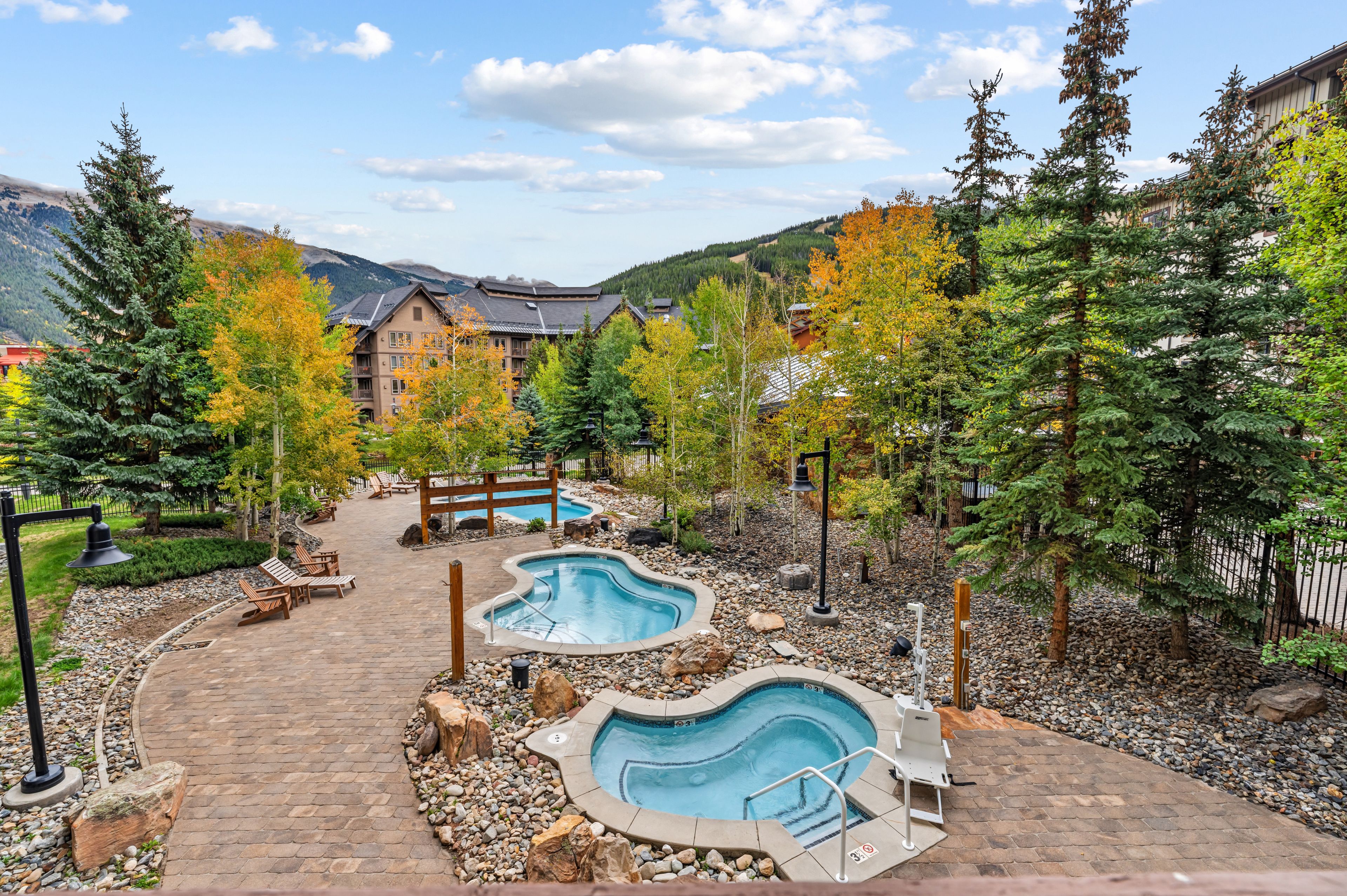 A resort with a pool area, wooden deck, and mountain views.