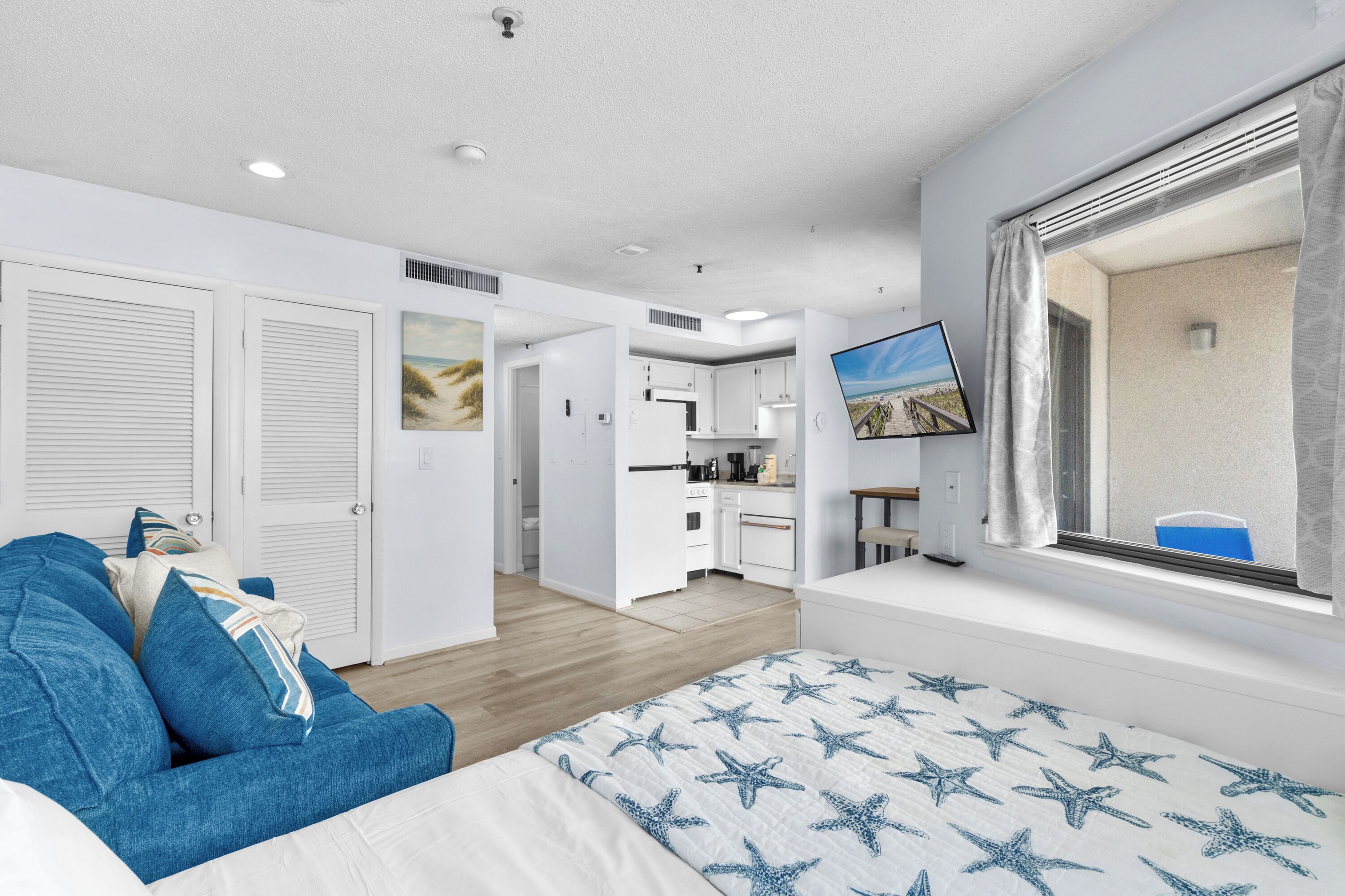 Un dormitorio con cama, sofá, televisor y ventana con vistas.