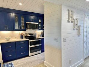 Eine moderne Küche mit dunkelblauen Schränken, Edelstahlgeräten und einer weißen Spritzschutzwand.