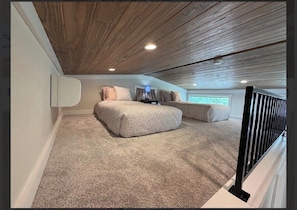 A bedroom with a sloped ceiling, a bed, a bedside table, and a window. - Magnolia Modern Tiny Home (Vicksburg)