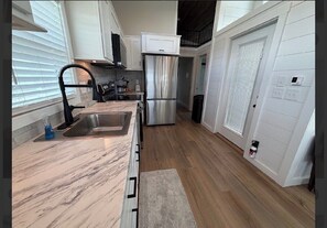 A modern kitchen with a stainless steel refrigerator, a sink, and wooden countertops. - Magnolia Modern Tiny Home (Vicksburg)