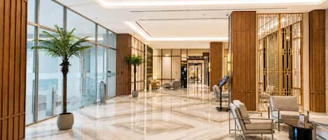 A spacious lobby with a marble floor, seating area, and a reception desk.