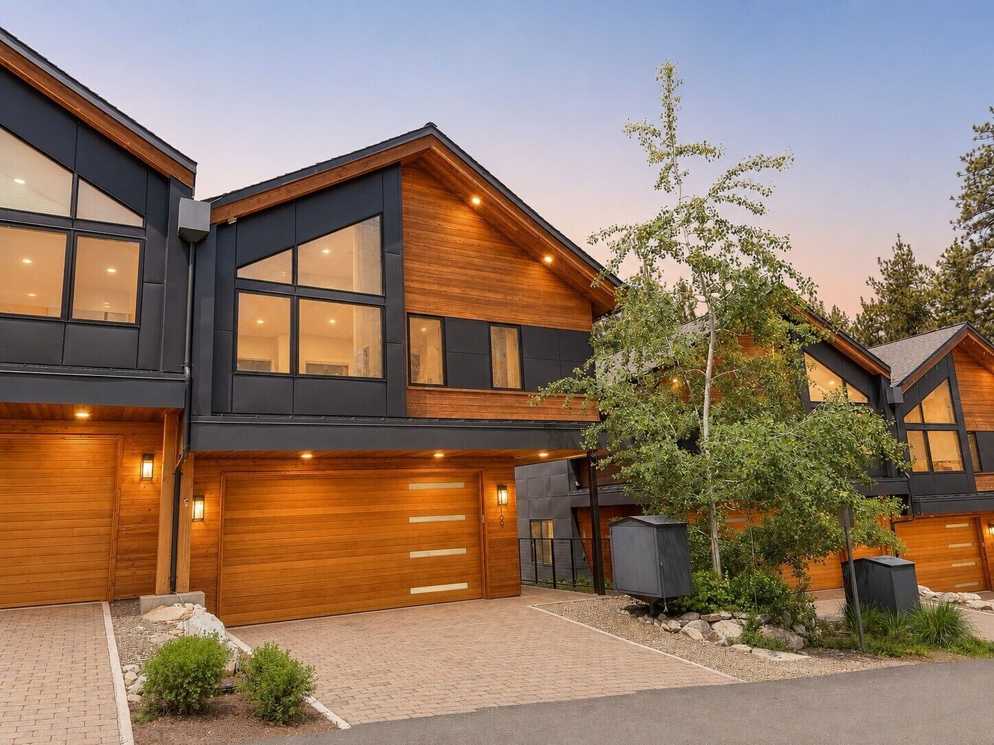 A modern two-story house with large windows, a garage, and a well-maintained garden.
