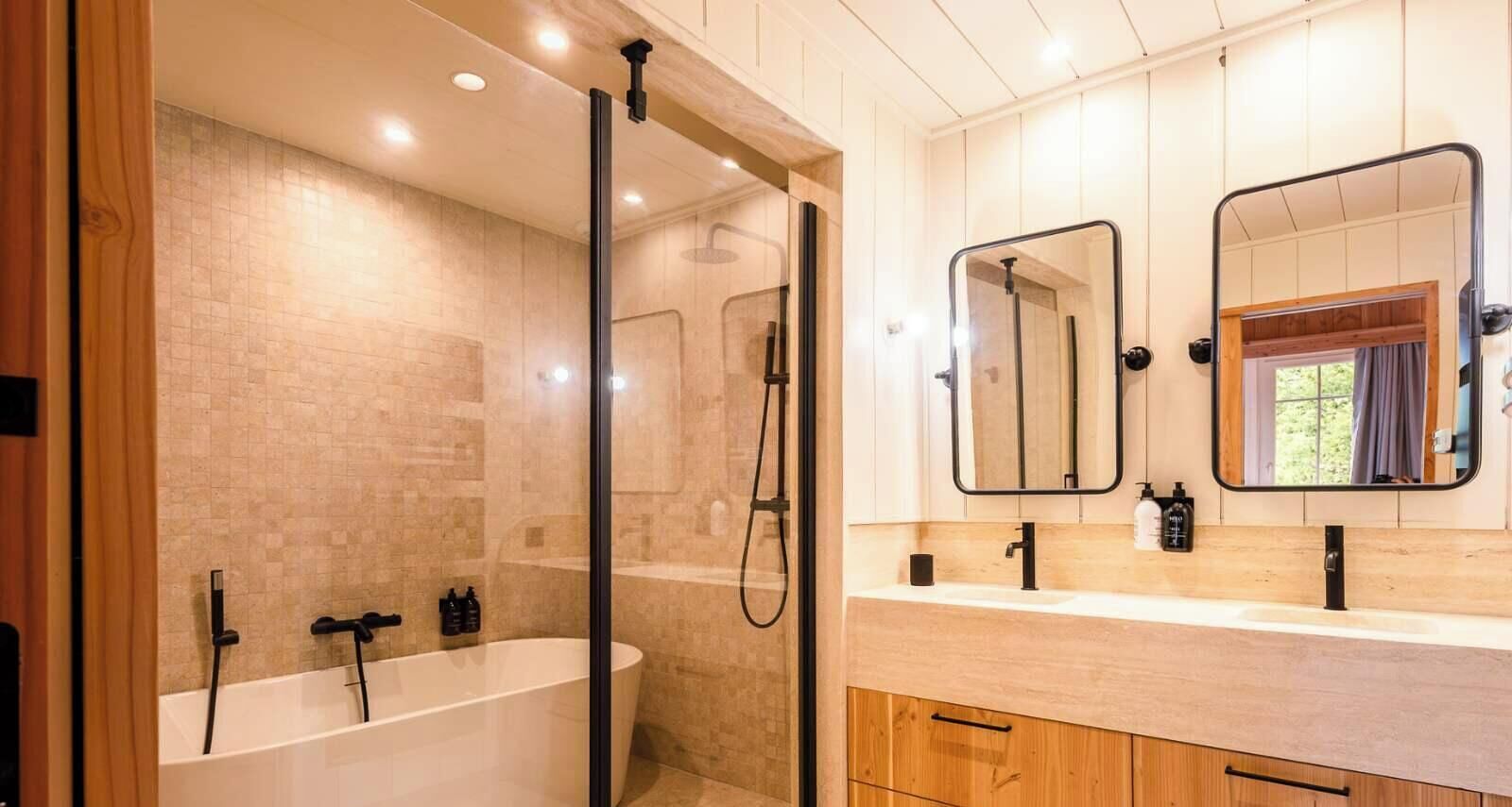 Et moderne badeværelse med et fritstående badekar, en bruseniche og et toiletbord med spejl.