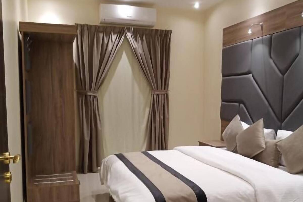 A bedroom with a bed, curtains, a headboard, and a door.
