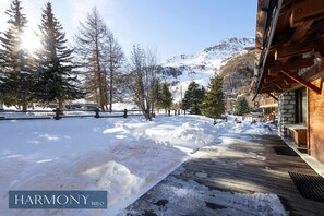 A wooden building with a snow-covered deck and a mountainous backdrop. - Ancolie HARMONY Suite by HILO Collection (Val-d'Isère)