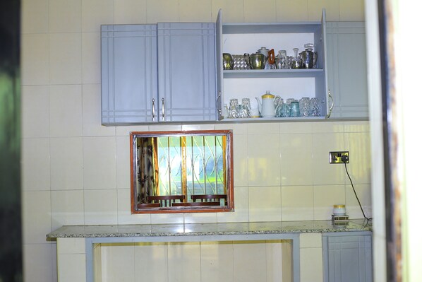 A kitchen with light blue cabinets, a window with a metal grill, and a countertop with a small appliance.
