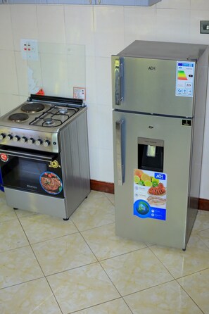 Eine Küche mit Edelstahlherd und Kühlschrank, einem Wasserspender und einem gefliesten Boden.