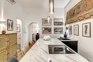 A modern kitchen with a marble countertop, pendant lighting, and artwork on the walls. - BoHo Studio & Terrace (Roma)
