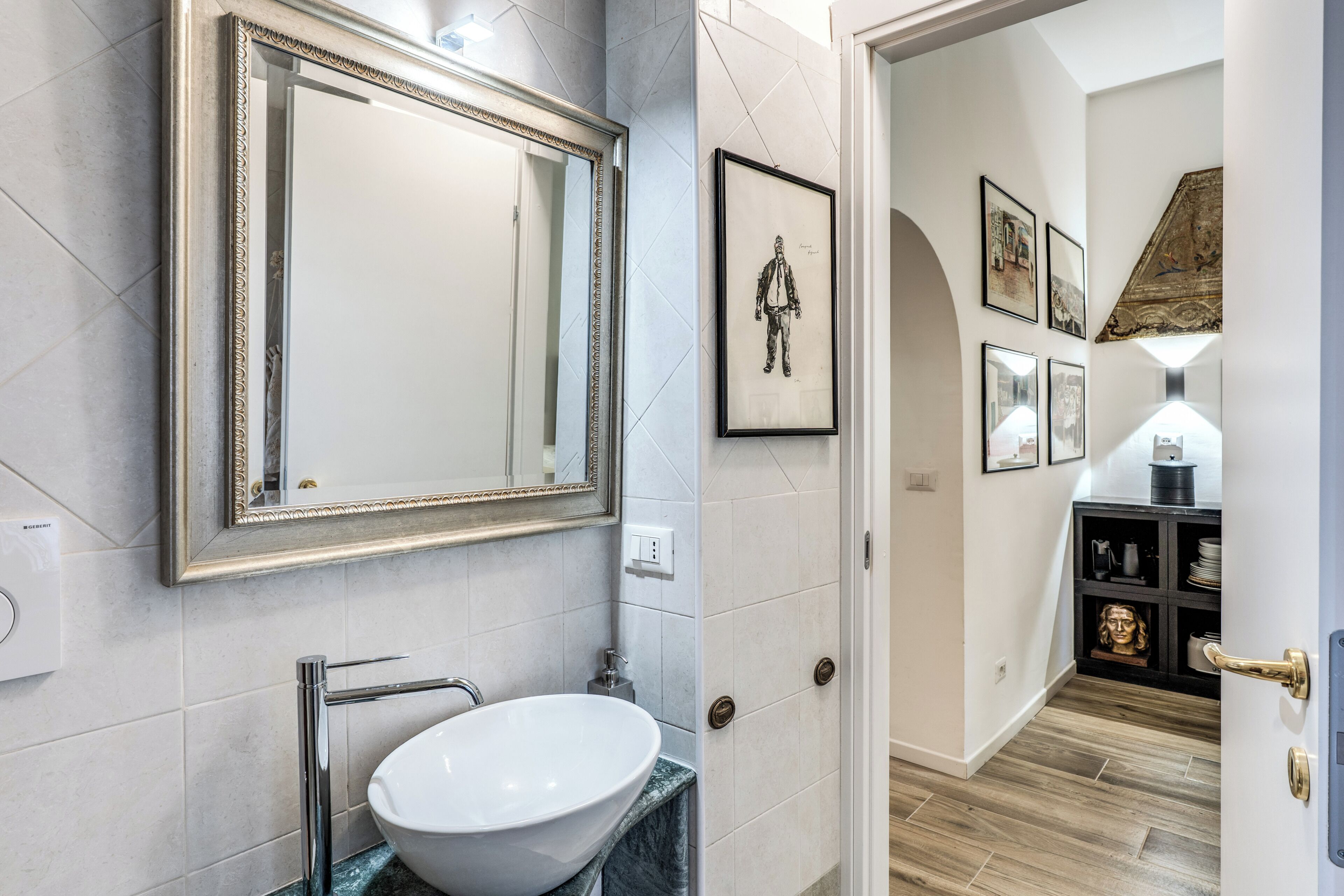 A bathroom with a large mirror, a white sink, and a tiled floor.