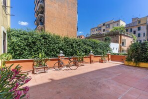 A courtyard with a bicycle, potted plants, and a tiled floor. - BoHo Studio & Terrace (Roma)