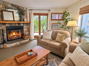 A cozy living room with a stone fireplace, a sofa, a coffee table, and a lamp.