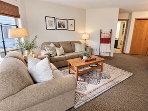 A living room with a sofa, a coffee table, and a patterned rug.
