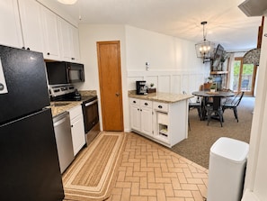 A compact kitchen with white cabinets, a black refrigerator, a microwave, and a coffee maker.