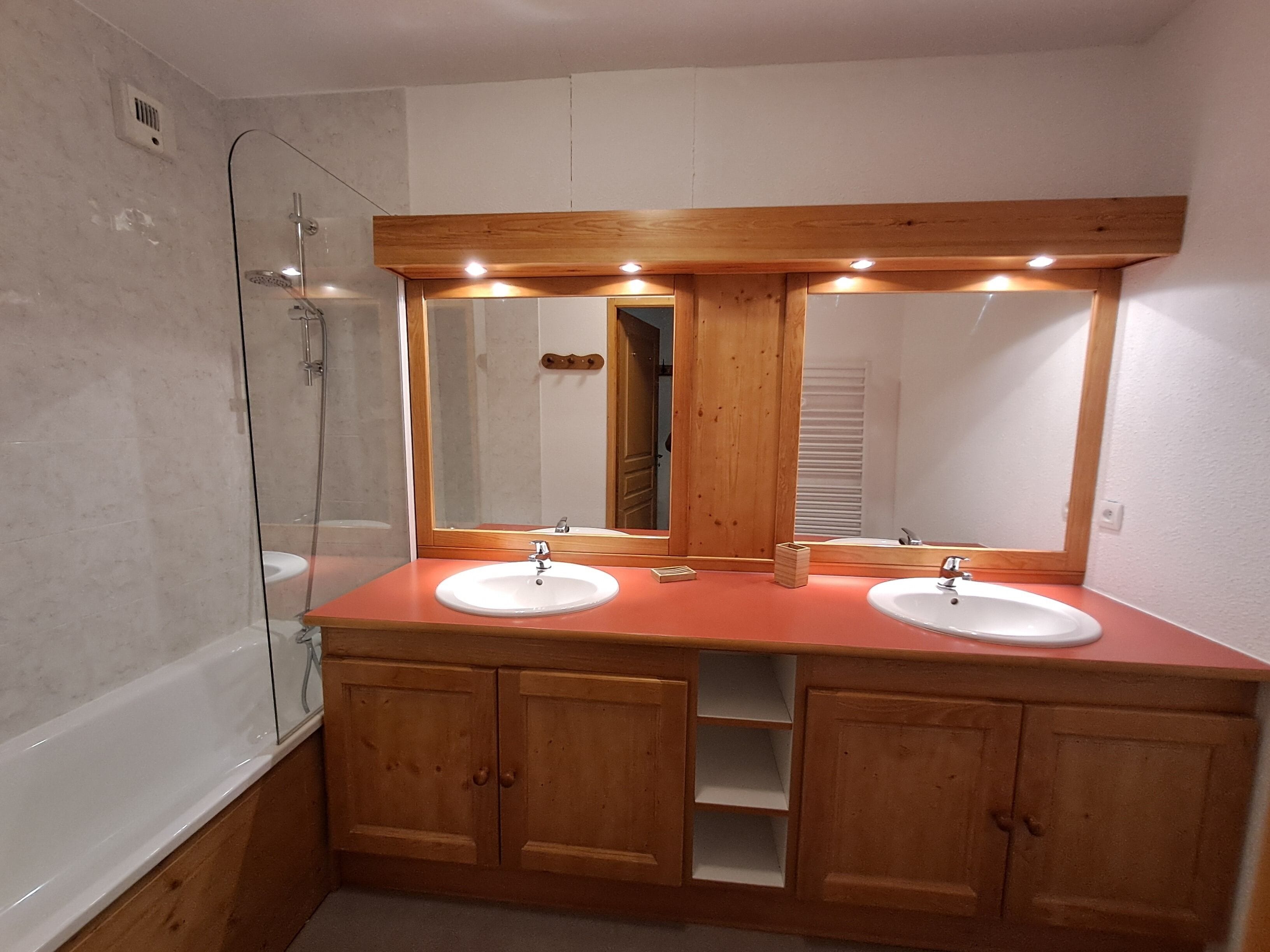 Une salle de bain avec deux lavabos, une douche en verre et des meubles en bois.