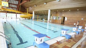 Ein Hallenbad mit Bahnen, nummerierten Startblöcken und einer Holzdecke.