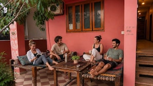 A group of people sitting on a bench in a room with a checkered floor, a table, and a potted plant.