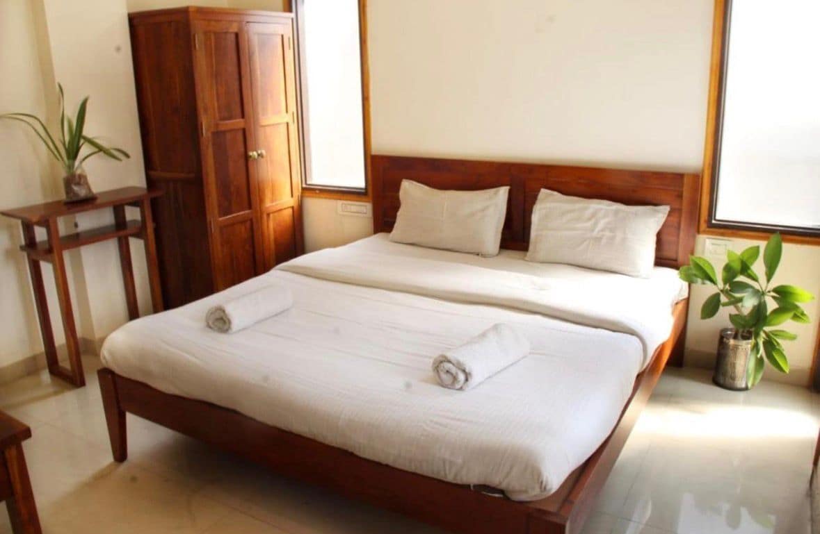 A double bed with white linens, a wooden headboard, and two pillows.