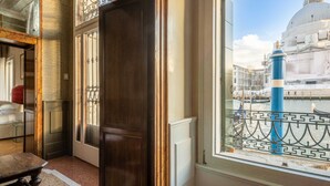 A room with a view of a historic building, a window with a decorative grille, and a door with a wooden frame. - Grand Canal Luxury Apartment with Private Terrace Steps from St. Mark's Square (Venezia)