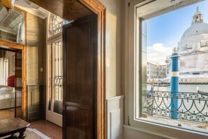 A room with a view of a historic building, a window with a decorative grille, and a door with a wooden frame. - Grand Canal Luxury Apartment with Private Terrace Steps from St. Mark's Square (Venezia)