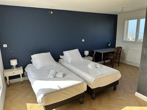 Ein Hotelzimmer mit zwei Betten, einem Schreibtisch und einem Stuhl.