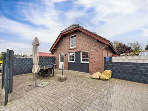 Ein Ziegelhaus mit Garage, einer Terrasse mit Tisch und Stühlen sowie einem überdachten Außenbereich.