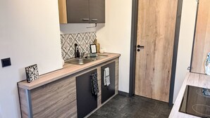 Une cuisine compacte dotée d’un plan de travail en bois, d’un évier encastré et d’une porte avec un cadre en bois.