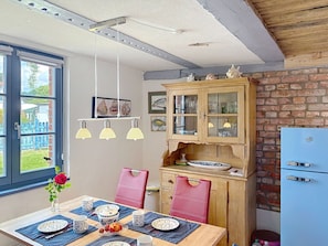 A dining area with a table set for four, a wooden cabinet with glass doors, and a blue refrigerator.