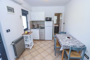 A compact kitchen with white cabinets, a microwave, and a small dining area with a table and chairs. - Apartment A2 Villa Irena Poreč (Poreč)
