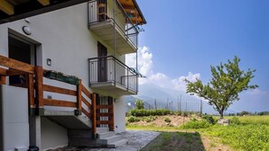 Un edificio a due piani con un balcone, una scala in pietra e vista su una montagna.