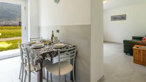 Un'area pranzo con un tavolo apparecchiato per quattro persone, un divano verde e un quadro appeso al muro.