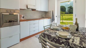 Una cucina moderna con mobili bianchi, forno integrato e zona pranzo con tavolo apparecchiato per due.