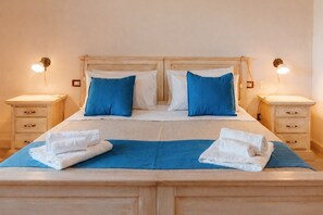 A double bed with two pillows, a blue bedspread, two bedside tables with lamps, and a wooden headboard. - Villa [2 suites] 5 minutes from the sea | air conditioning | garden | BBQ | outdoor shower (Diso)