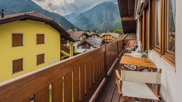Un balcón con barandilla de madera con vistas a un pueblo de montaña con casas tradicionales.