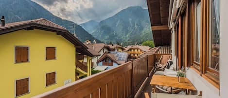 Un balcón con barandilla de madera con vistas a un pueblo de montaña con casas tradicionales.