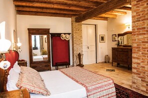 Ein Schlafzimmer mit einem Bett, einem Schminktisch, einem Spiegel, einer Tür und einer Ziegelwand.