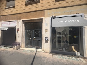 Un edificio con locales comerciales, incluyendo uno llamado 'Estetica & Benessere' y otro llamado 'Temporary Store'.