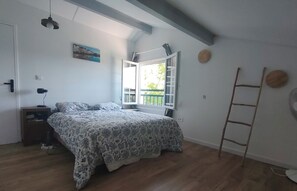 Ein Schlafzimmer mit einem Bett, einem Nachttisch, einem Fenster mit Vorhängen, einer Leiter und einem an der Wand hängenden Bild.
