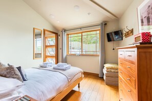 Ein Schlafzimmer mit Bett, einem Holzschrank, Fernseher und großen Fenstern.