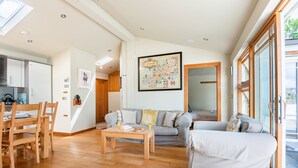 Ein geräumiger Wohnbereich mit Esstisch, zwei Sofas und einer Küche im Hintergrund.