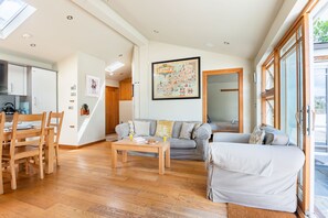 Ein geräumiger Wohnbereich mit Esstisch, zwei Sofas und einer Küche im Hintergrund.