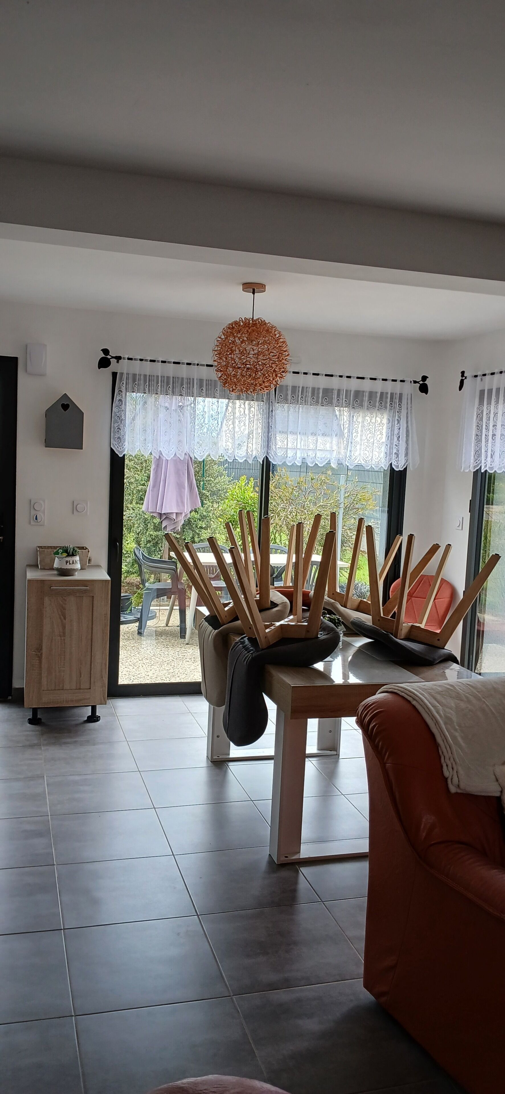 A modern living room with a dining area, large windows, and a view of the outdoors.